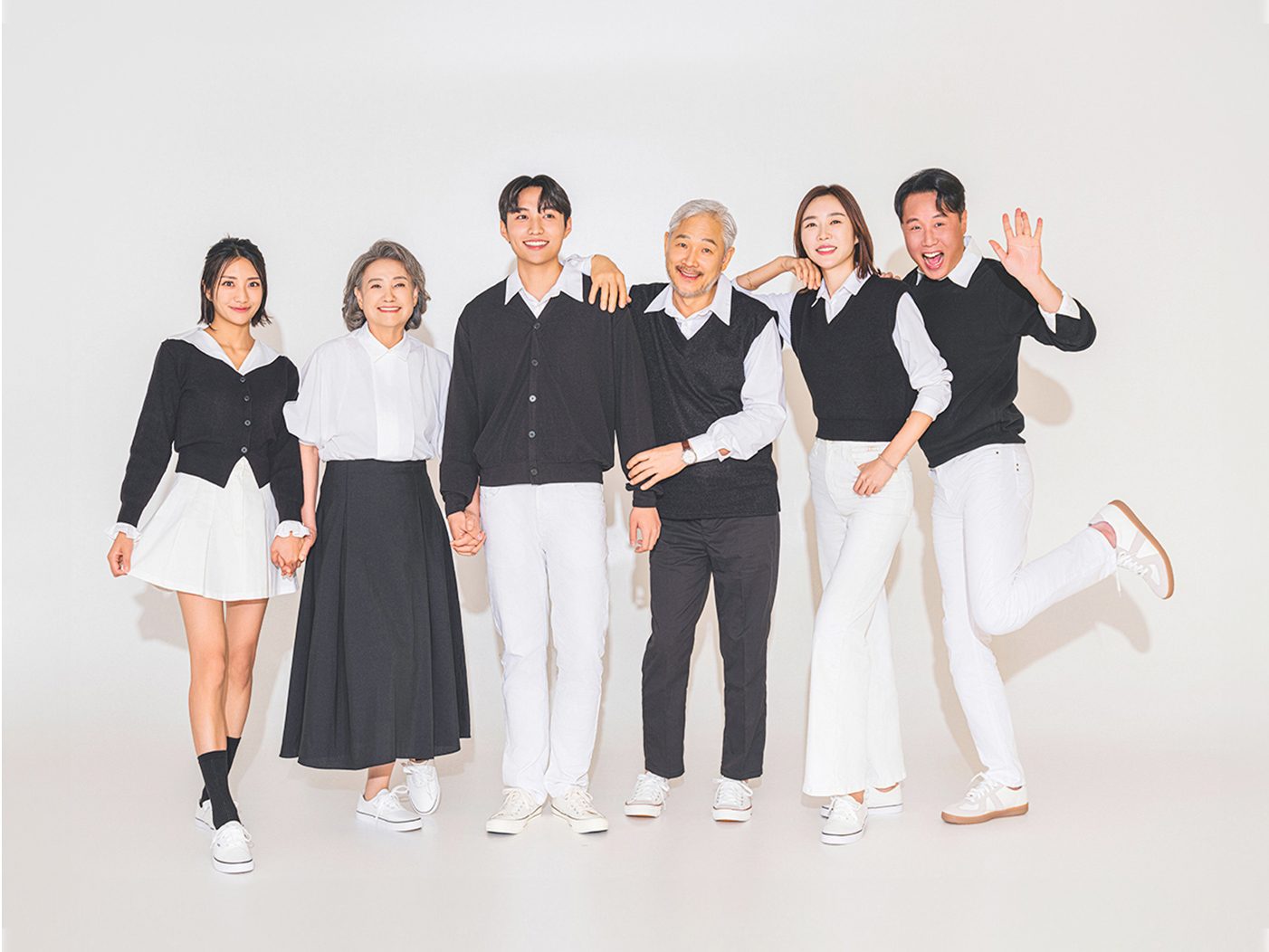 창원 블랙앤화이트 가족사진 — 여섯 식구가 손을 잡고 나란히. 흑백 톤의 옷이 배경과 한 덩어리로 보입니다