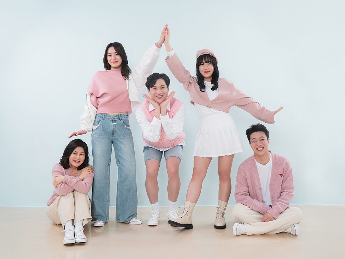 창원 캐주얼 가족사진 — 하늘색 벽과 연노란 바닥 앞에서 손을 맞잡고 꽃받침을 만든 다섯 사람