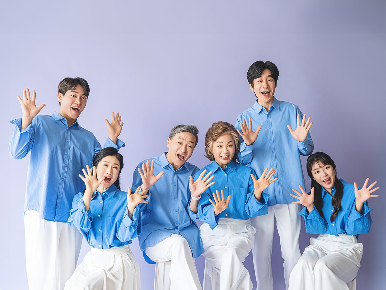 창원 캐주얼 가족사진 — 마지막 컷. 보라색 배경 앞에서 손바닥을 활짝 펴고 웃는 여섯 사람