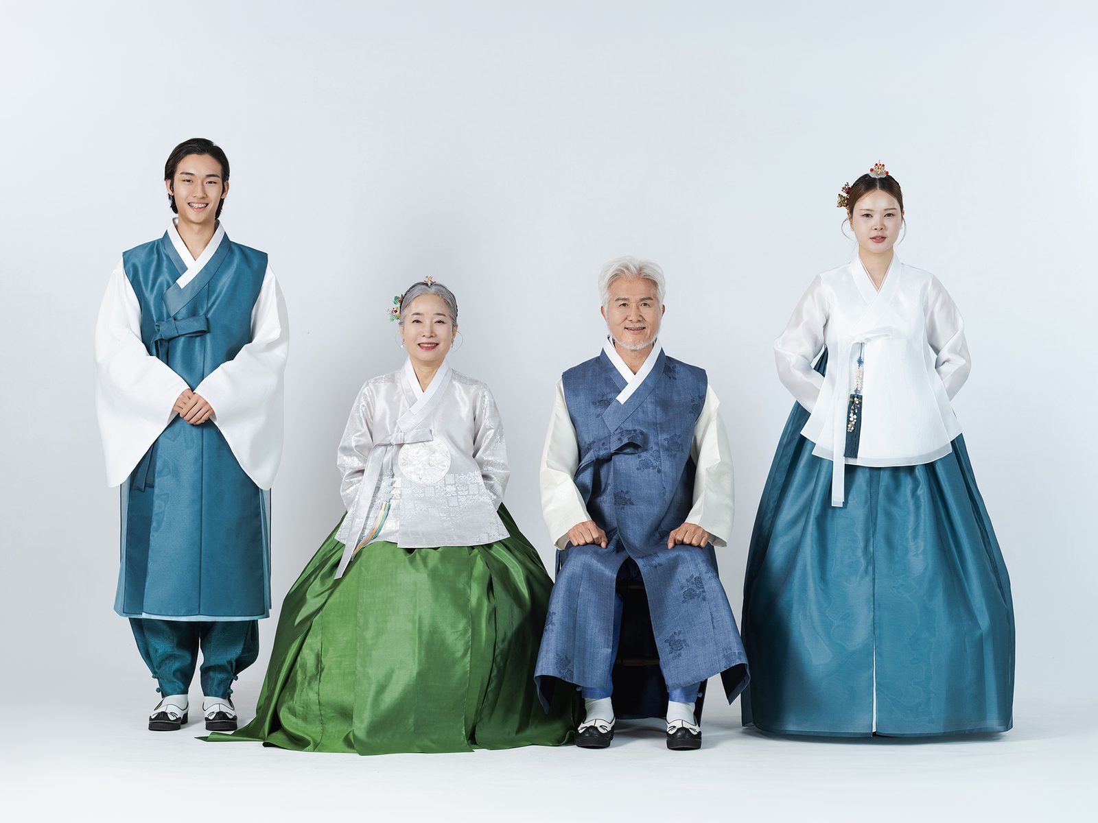 의령 한복 가족사진 — 네 사람. 할머니가 초록 치마로 가운데 앉고 할아버지가 남색 조끼를 입고 그 옆에 앉았습니다