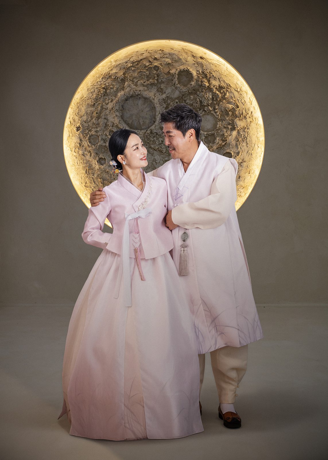 창원 한복 부부사진 — 커다란 보름달을 배경으로 선 두 사람. 분홍 저고리와 연분홍 두루마기가 달빛 아래에 놓였습니다