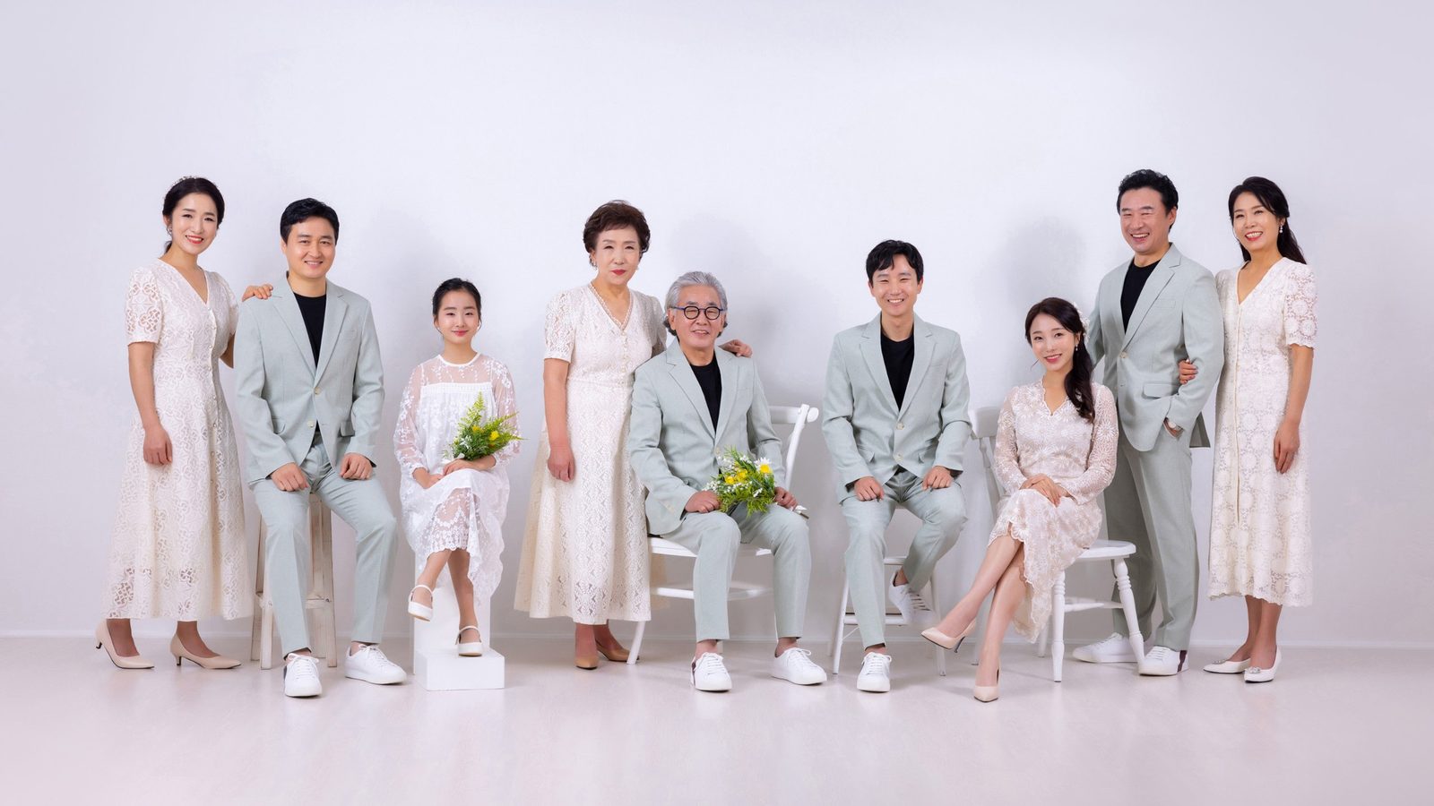 창원 세미웨딩 가족사진 — 여덟 사람이 흰 배경에 나란히. 세대가 섞여 있어도 옷 색이 같으면 한 가족으로 읽힙니다