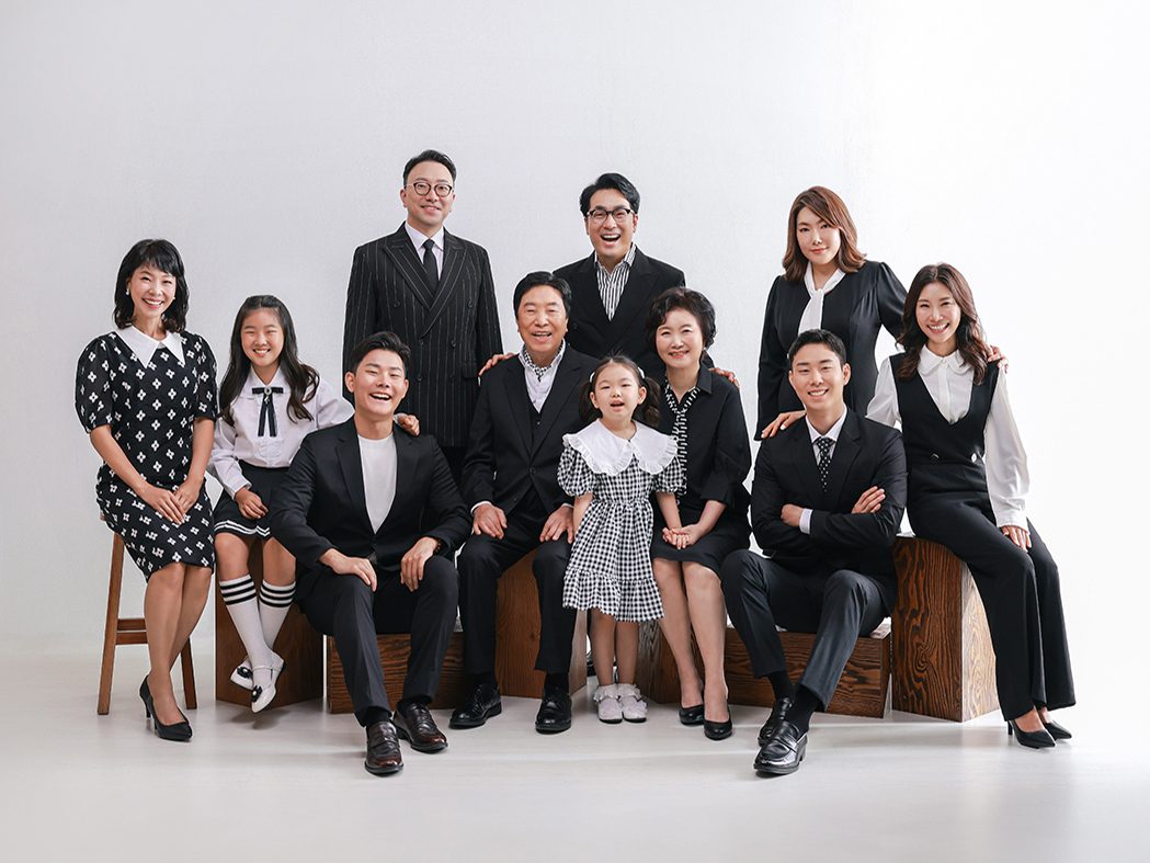 창원 정장 가족사진 — 나무 큐브에 앉고 선 세 대 식구. 할아버지 할머니를 가운데 두고 아들딸과 손주가 둘러섰습니다